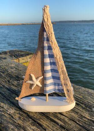 nautical wooden yacht in blues and whites with a hessian sail